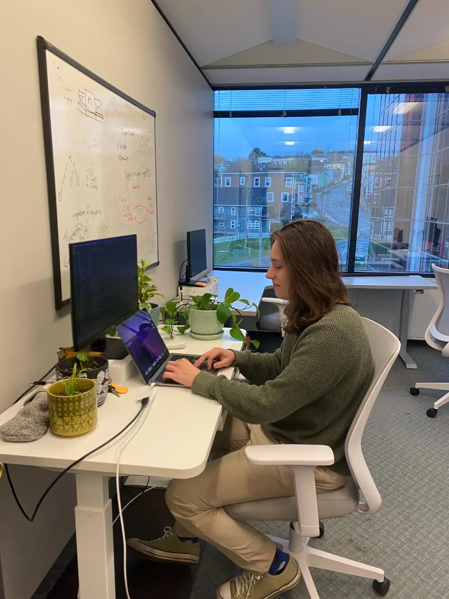 Joel working on a laptop at a standing desk in the office